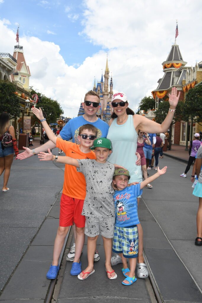 A family pose with smiles in front of the disney castle