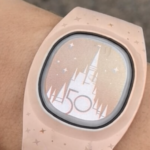 A light pink magic band on a wrist - its the 50th anniversary castle edition