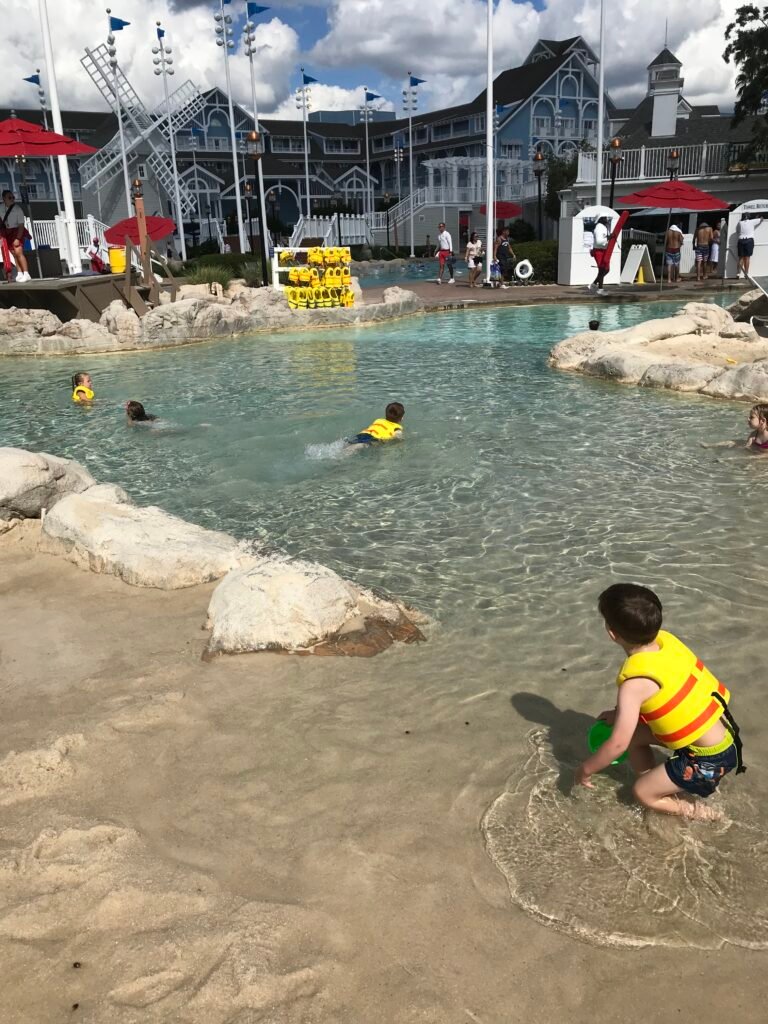 Disneys Beach Club resort pool area with some children playing in a shallow sand bottom pool