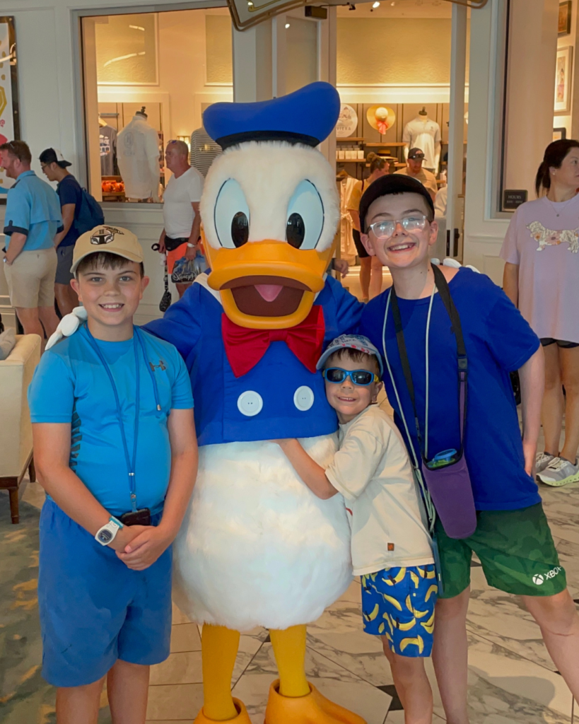 Three boys who are hugging Donald Duck at a Disney Resort Lobby, it was not heir first time.