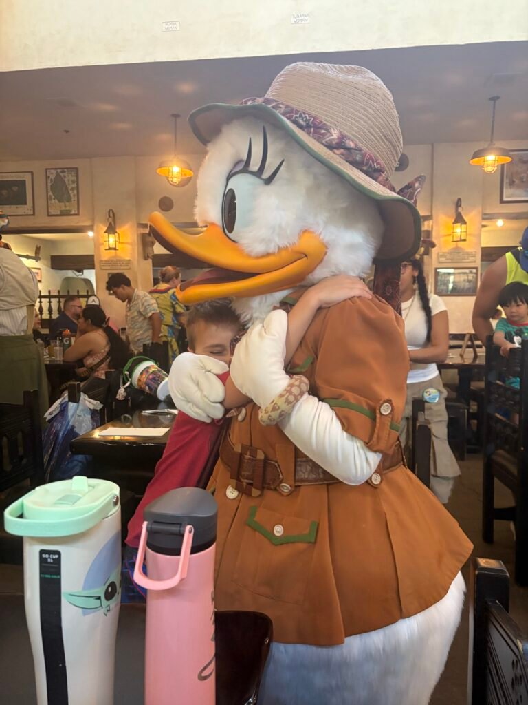 A small boys hugs Daisy Duck at a character restaurant - The hidden costs of a Disney Holiday