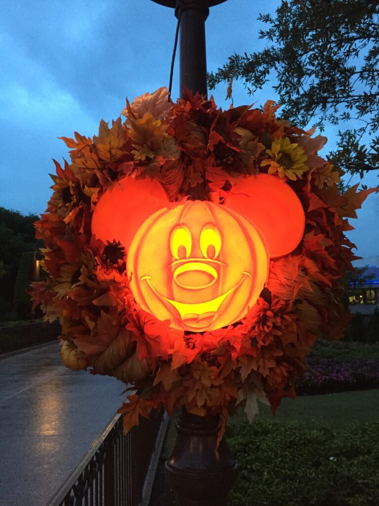 A large plastic Mickey shaped pumpkin attached to a lamp post in the magic kingdom glows orange - one of the Walt Disney world special events